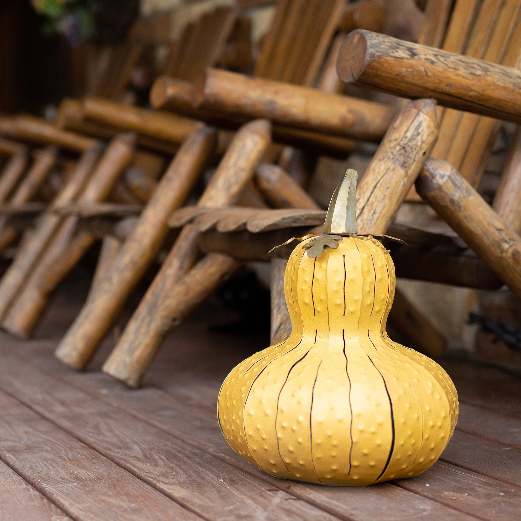 Yellow Gourd Luminary on porch by wooden chairs. 