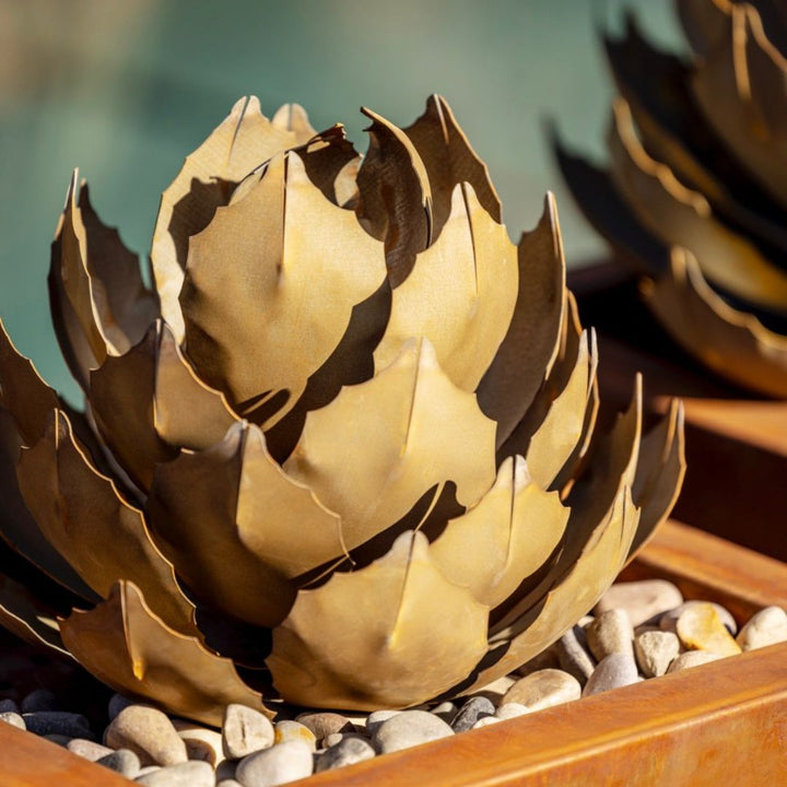 A small handcrafted metal artichoke agave sculpture inside a planter, close up shot.
