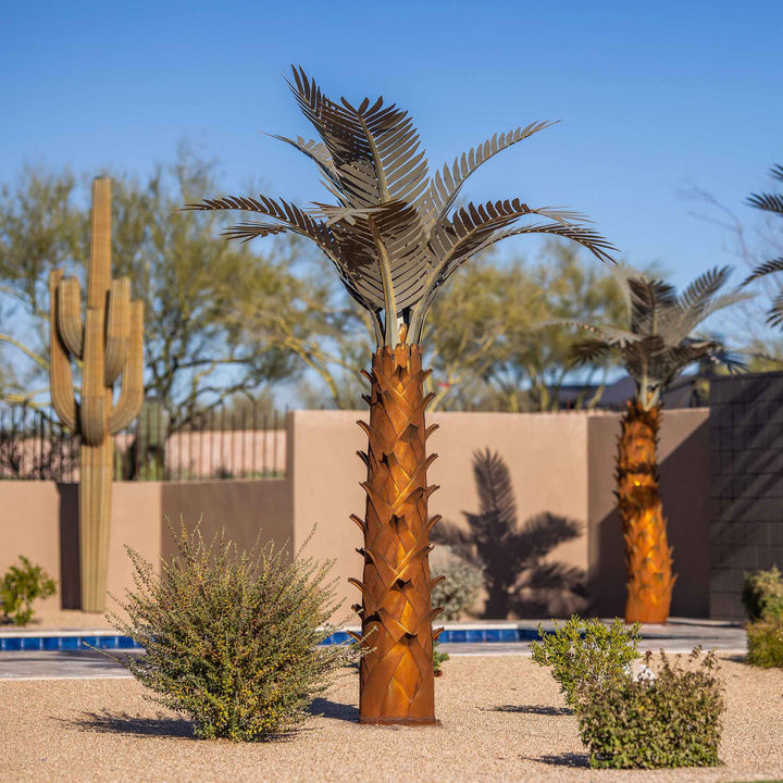 A large metal paradise palm tree, standing 10ft tall, located in a backyard near a pool. The sculpture's intricate design features realistic palm fronds and textured trunk, creating a lifelike appearance.