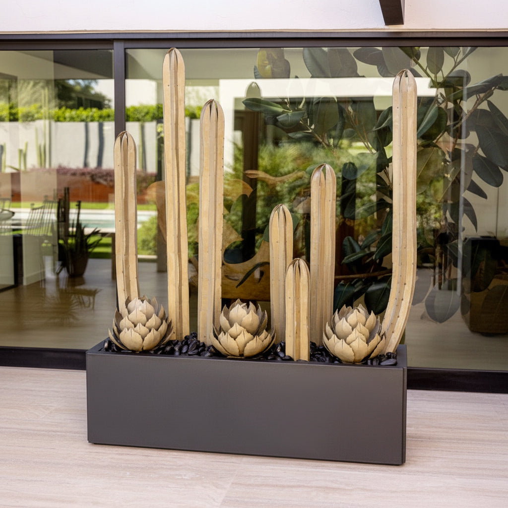 Decorative steel artichoke sculptures in a black planter against a reflective glass wall.