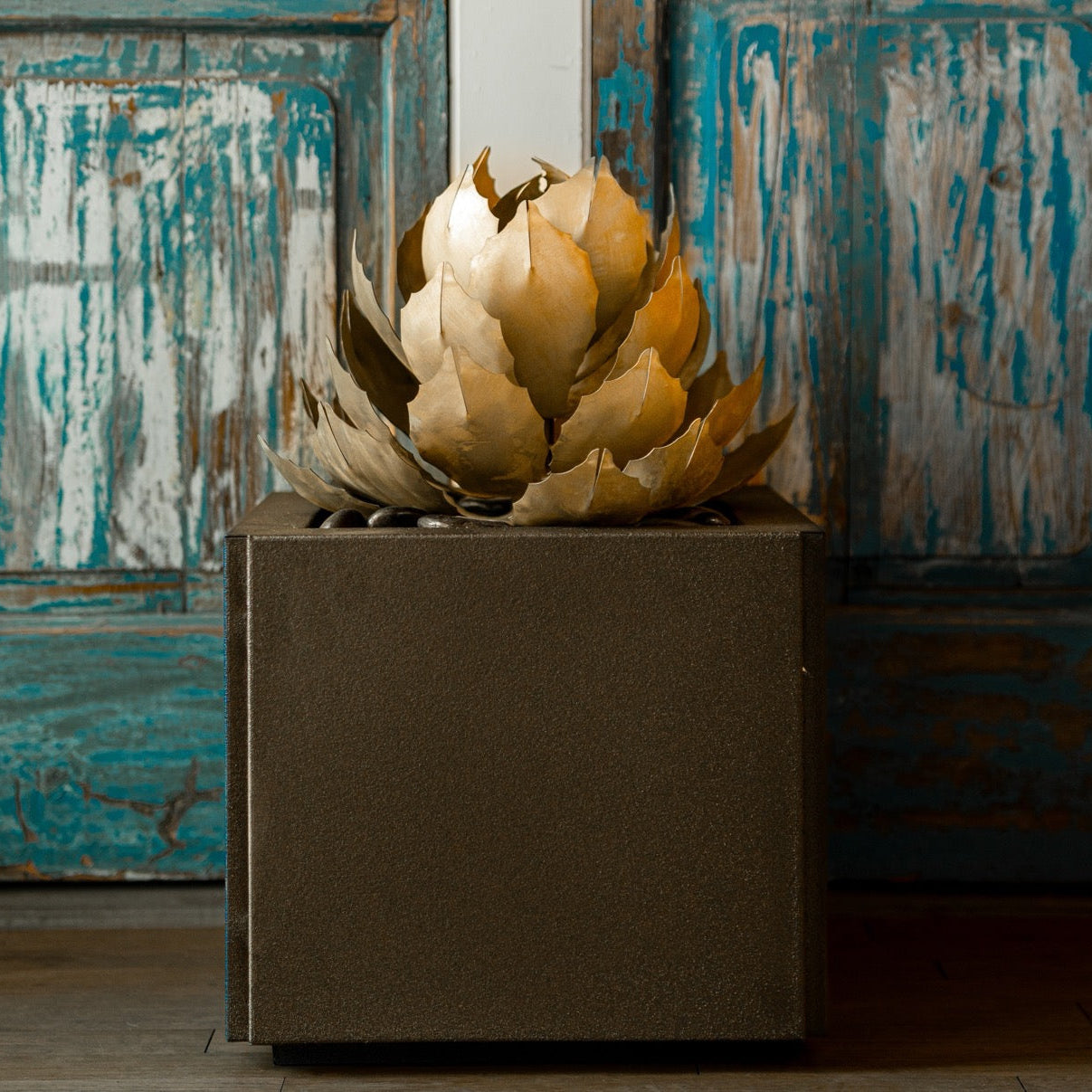 Decorative steel artichoke arrangement in a brown pot against a rustic wooden background