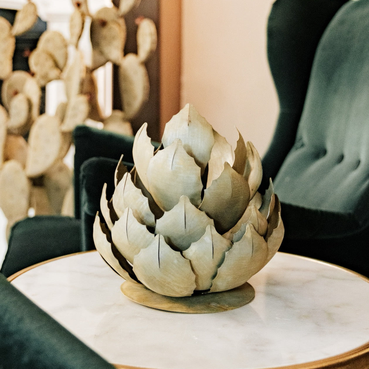 Decorative artichoke sculpture on a marble table with a blurred indoor background