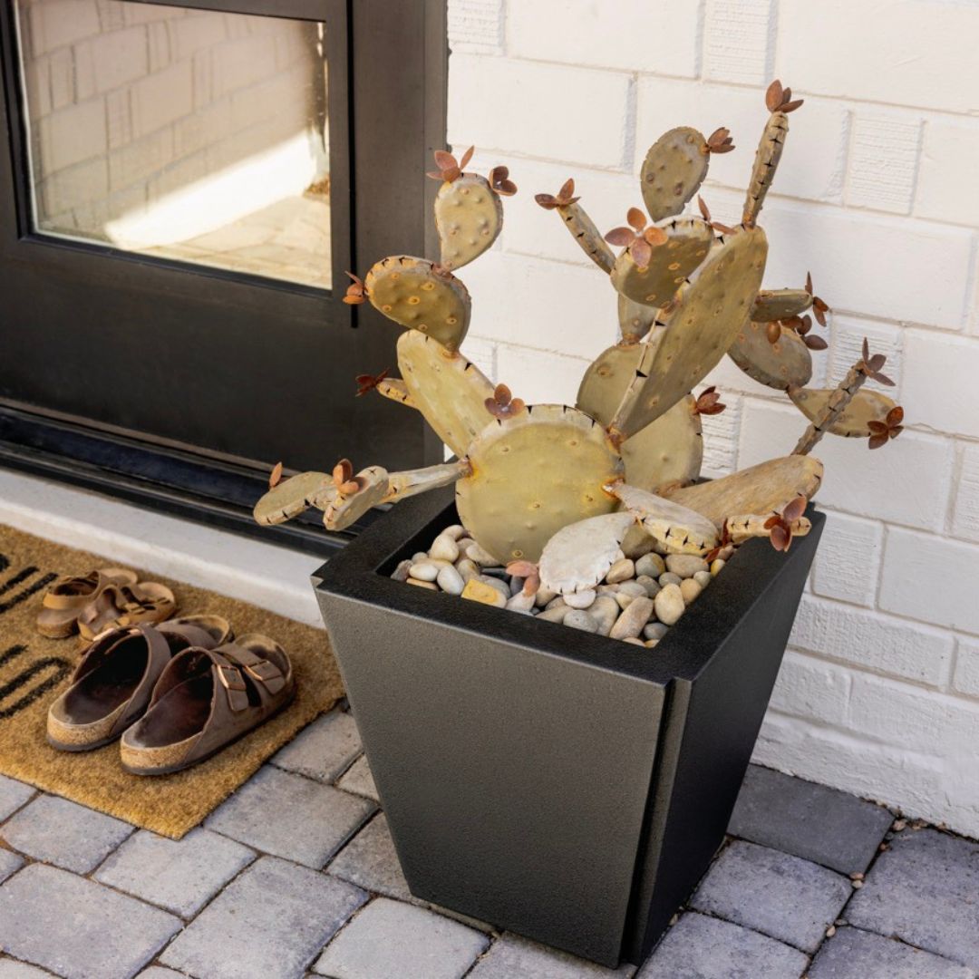 A handcrafted realistic metal prickly pear cactus in a black planter outside front door.