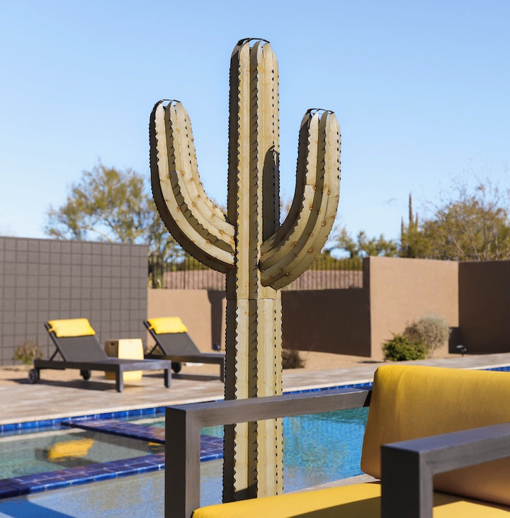 A metal saguaro cactus torch located poolside in the backyard. The sculpture's intricate design features a realistic saguaro body and arms, creating a lifelike appearance.