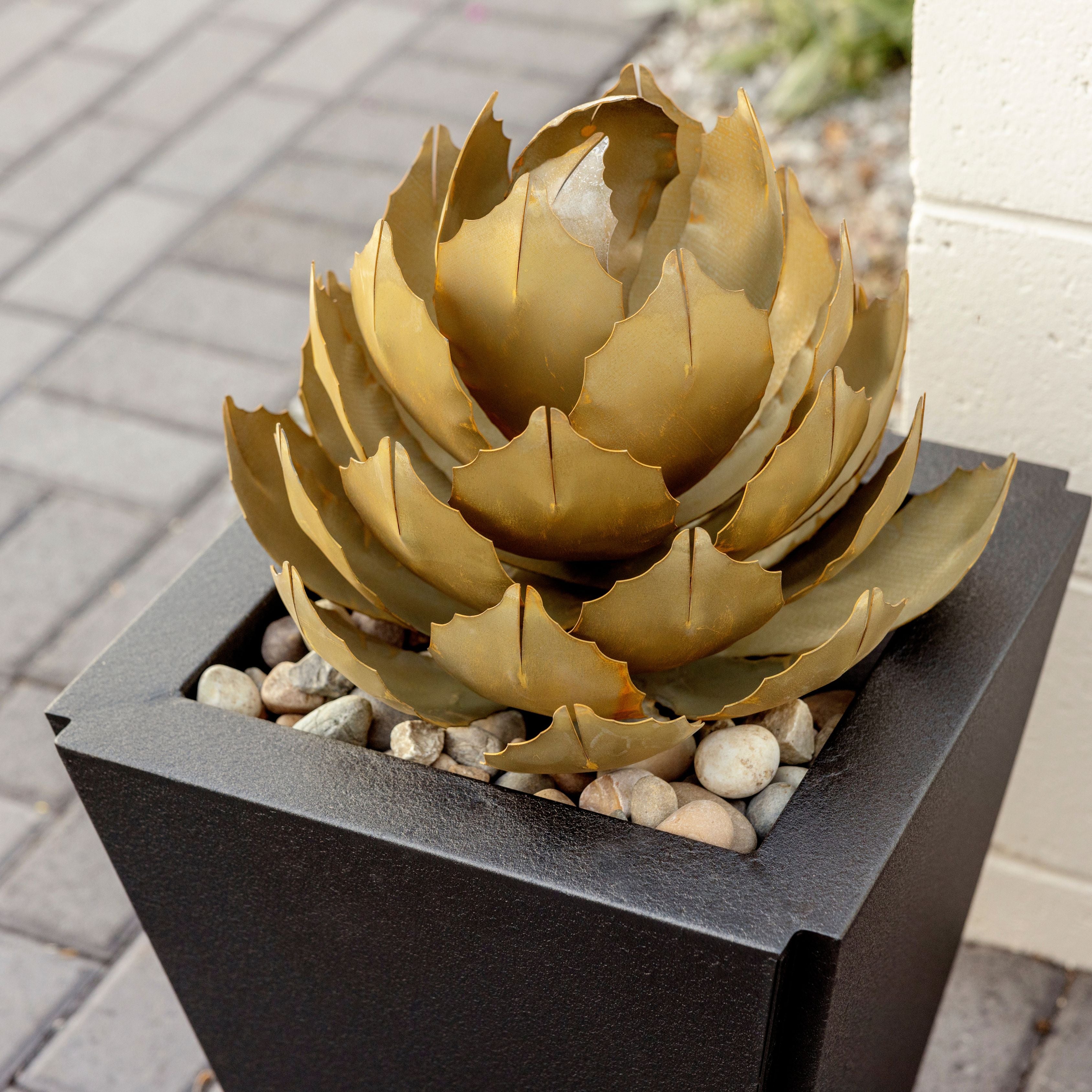 A close up shot of a handcrafted small metal artichoke agave in a parks planter in a garden landscaping. 