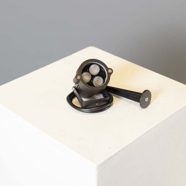 An led spotlight sculpture for saguaro spear, on a white table with a grey background.